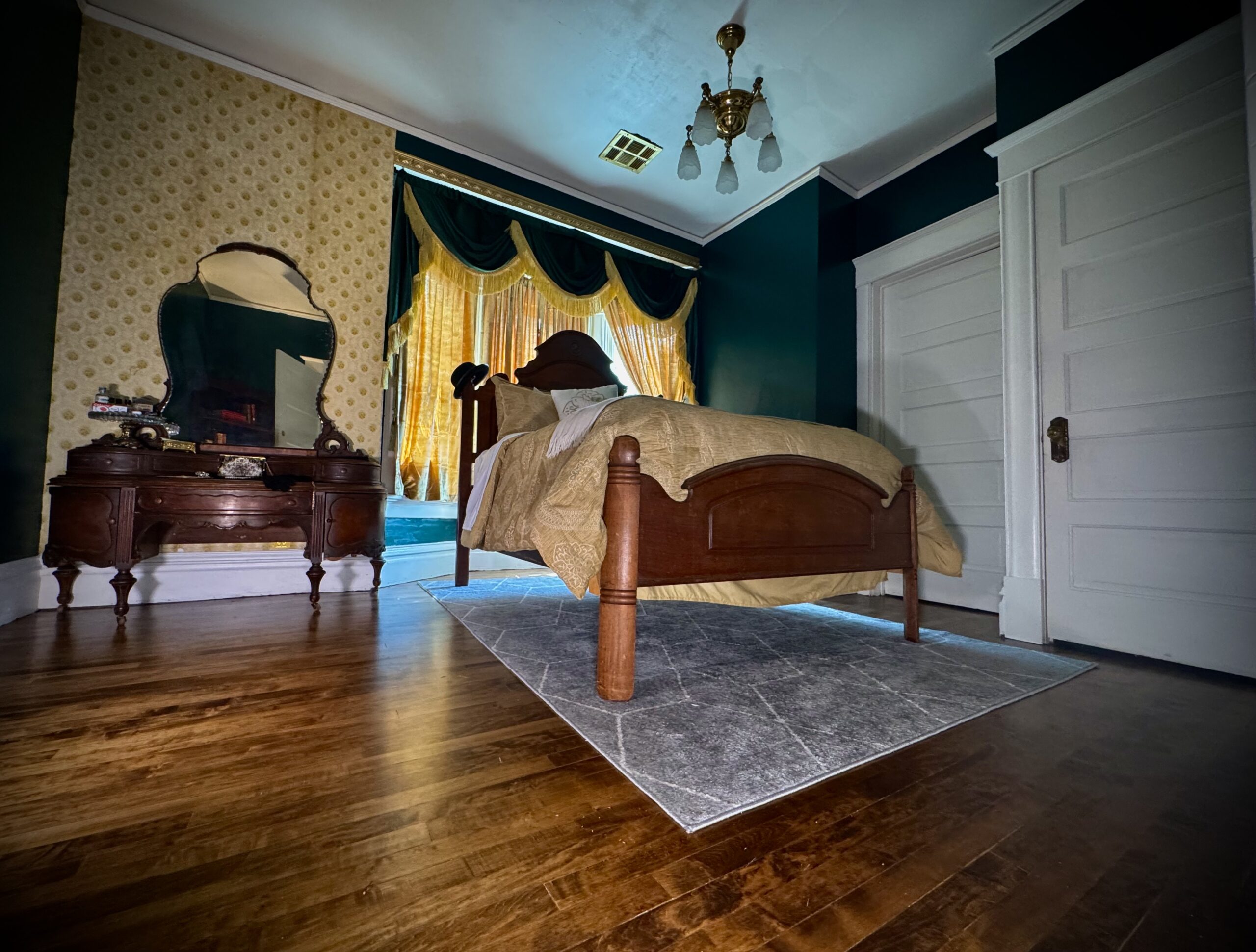 Wide view of Laura’s Room with antique bed, dresser, original wood floors, and period light fixture at Fears House